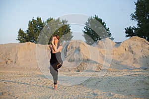 young woman doing eagle yoga pose outdoors