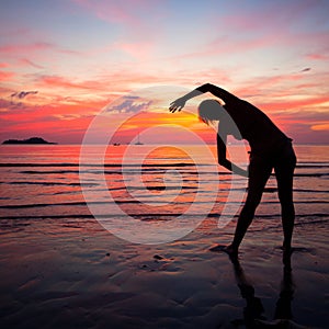 Young woman doing exercise on the beach