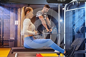 Young woman doing exercise with cable rowing crossover machine at gym.