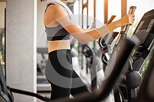 Young woman doing exercise cardio on elliptical trainer at gym