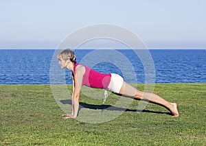 Young woman doing exercise on green grass