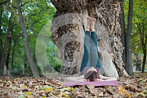 young woman doing exercise next to the tree