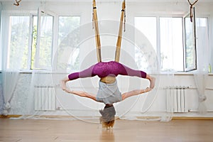 Young woman doing exercises of aerial yoga in hammock