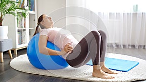 Young woman doing exercises on blue fitball at home. Concept of healthcare, sports and yoga at home