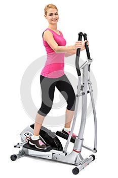 Young woman doing exercises on elliptical trainer