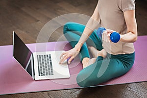 Young woman doing exercises at home. Online video training. Girl using laptop for fitness