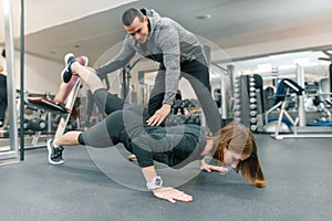 Young woman doing exercises with personal instructor in gym. Sport, athlete, training, healthy lifestyle and people concept