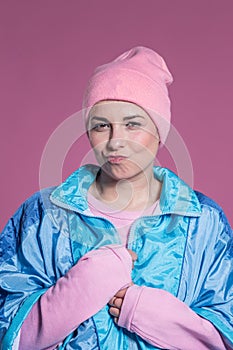 Young woman doing facial expressions against a pink background