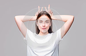 Young woman doing funny gesture with finger over head as bull horns. Crazy funny sexy girl doing funny gesture with
