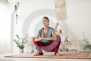Young woman doing garland pose at yoga studio