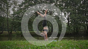 A young woman is doing gymnastic exercises in a summer park in a tracksuit. Healthy lifestyle.