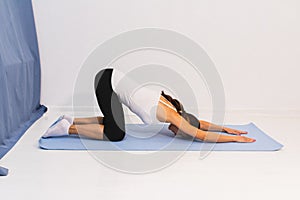 young woman is doing gymnastics on a yoga mat or pilates mat.