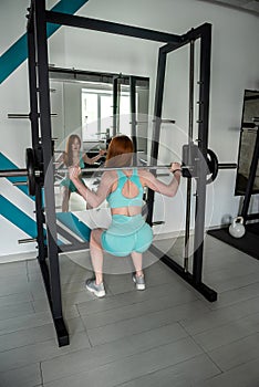 young woman doing hard exercise lifting weights at gym club