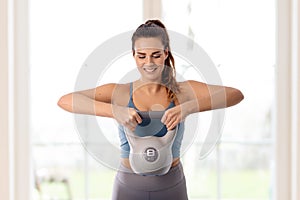Young woman doing home workout with kettlebell