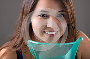 Young woman doing inhalation with a medical vaporizer nebulizer machine on grey background