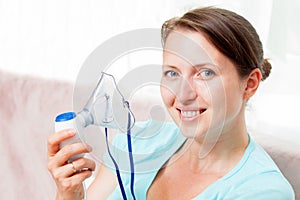 Young woman doing inhalation with a nebulizer at home