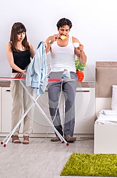 Young woman doing ironing for her husband