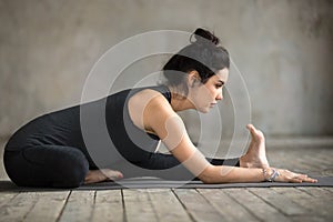 Young woman doing Janu Sirsasana exercise