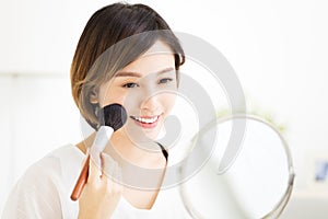 Young woman doing makeup in front of the mirror