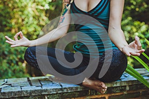 A Young woman doing meditation outdoors in tranquil environment