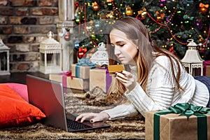 Young woman doing online shopping with credit card and laptop at home. Christmas shopping concept