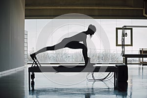 Flexible Female Using Pilates Reformer Machine In Gym photo