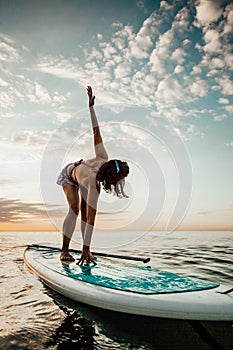 Young woman doing Pilates on a SUP board