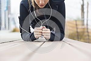 Young woman doing plank exercise working on abdominal muscles and triceps at outdoor