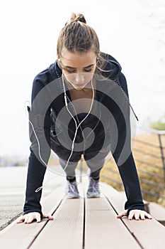 Young woman doing plank exercise working on abdominal muscles and triceps at outdoor
