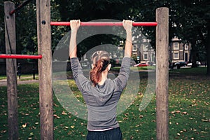 Young woman doing pullups in the park