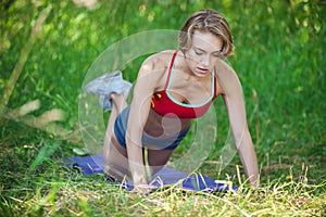 Young woman doing push ups exercise outdoors