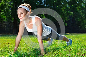 Young woman doing push ups on green