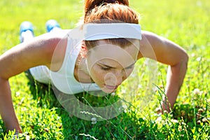 Young woman doing push ups on green