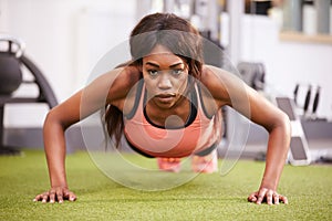 Young woman doing push ups at a gym