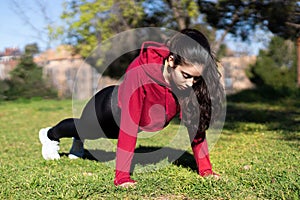 Young woman doing push-ups in a park in then morning. workout and health