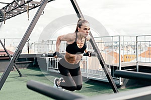 Young woman doing push ups at power rack