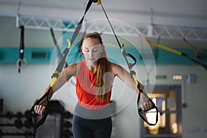 Young woman doing push ups on the TRX.