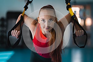 Young woman doing push ups on the TRX.