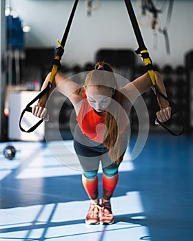 Young woman doing push ups on the TRX.