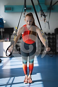 Young woman doing push ups on the TRX.