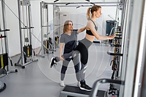 Young woman doing rehabilitation exercises with personal instructor on the kinesi machine.