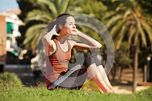 Young woman doing sit up exercise in park