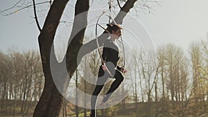 Young woman doing some acrobatic elements on aerial hoop outdoors in slow-mo