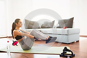 Young woman doing sport workout in room during quarantine. Girl doing abs exercise. Hold legs in air and hands parallel