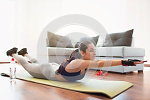 Young woman doing sport workout in room during quarantine. Lying on mat and stratching forward with hands. Home