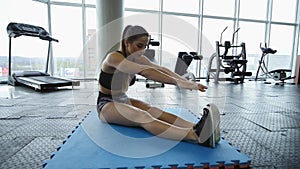 Young woman doing stretch exercise in gym