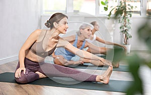 Young woman doing stretching asana Janu Sirsasana in yoga studio