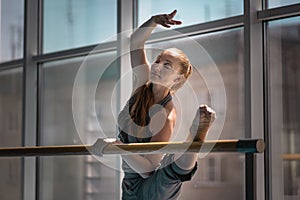 Young woman doing stretching on ballet barre.