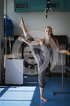 Young woman doing stretching on ballet barre.