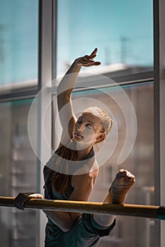 Young woman doing stretching on ballet barre.